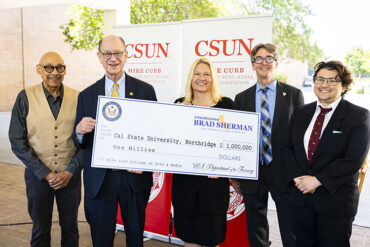Five people stand holding large ceremonial check.