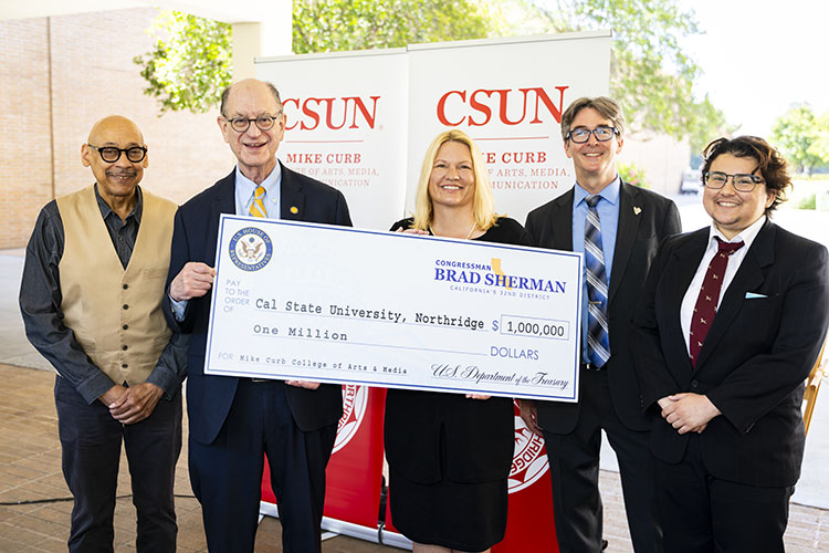 Five people stand holding large ceremonial check.