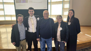 Five people stand in a line to pose for a photo.