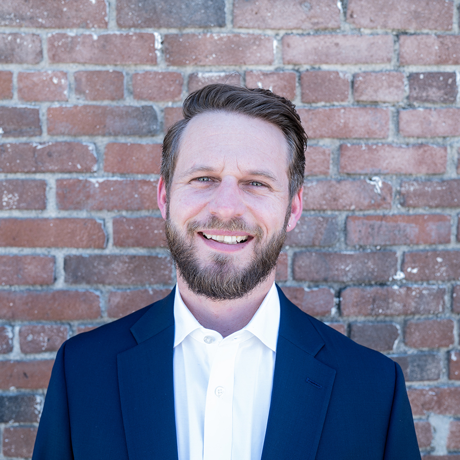 Portrait of CSUN alum Chris Nosala in front of a brick wall.