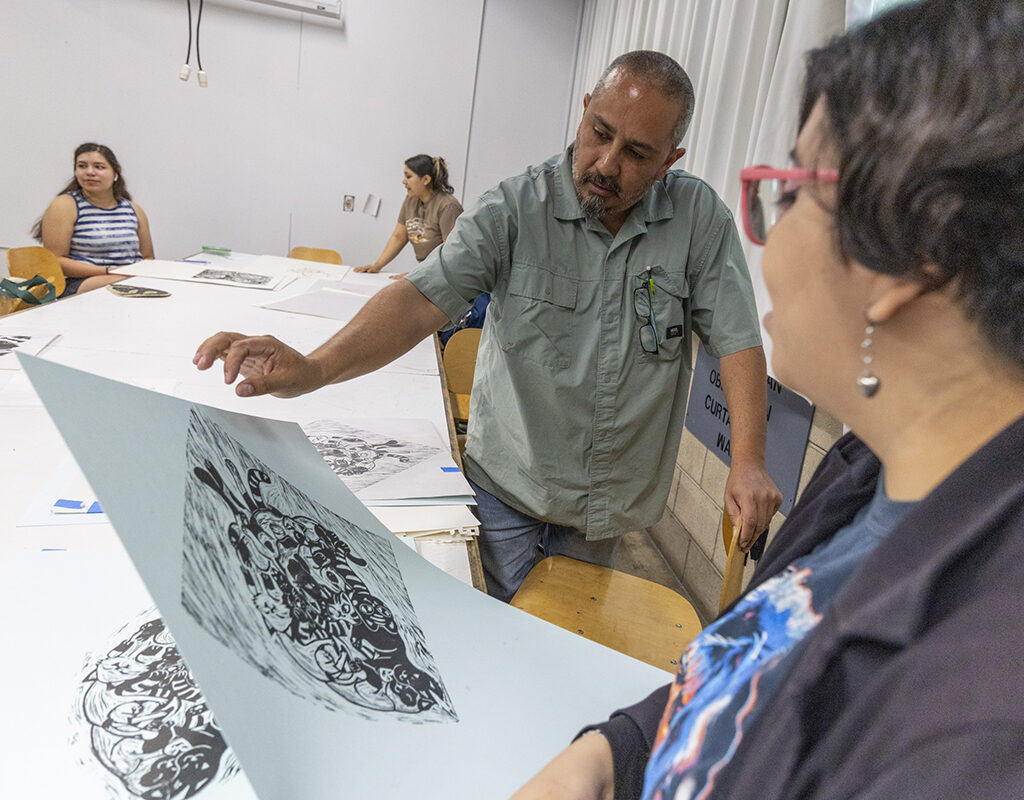 A man examines a student's print design at CSUN.