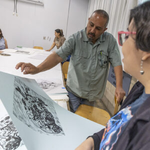 A man examines a student's print design at CSUN.