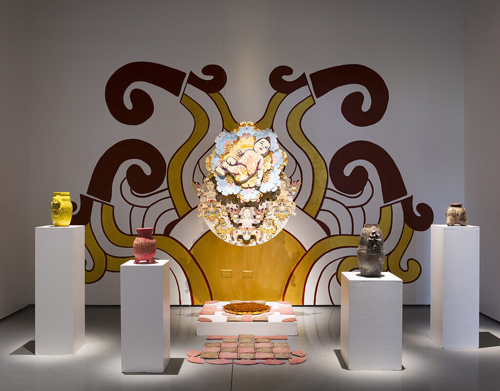 A baby, four ceramic vessels and a painted wall form the centerpieces of an art exhibit.