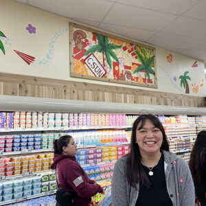 Student Mailahguiya Sourgose smiles below her mural displayed above a cold case.