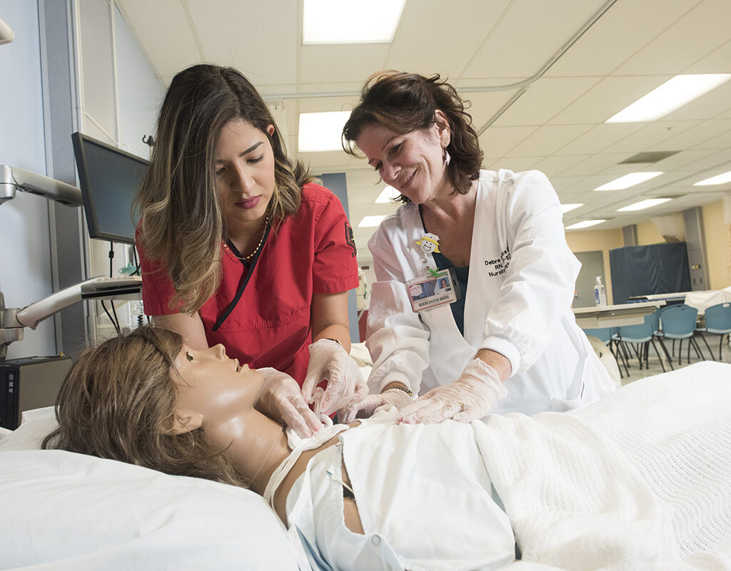A student works with a mannequin in CSUN's nursing simulation lab, supervised by a faculty member.