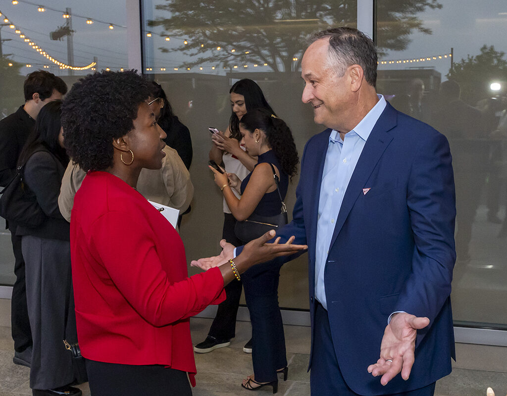 A woman has a conversation with former Second Gentleman Doug Emhoff at an event.