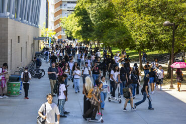 Crowds of students walk on the pathway by Manzanita Hall.
