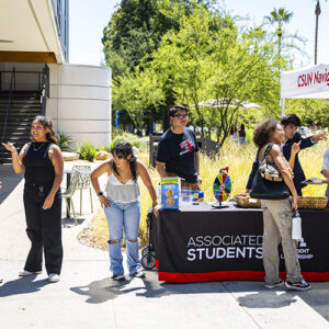 Students stand outside by a table that says "Associated Students."