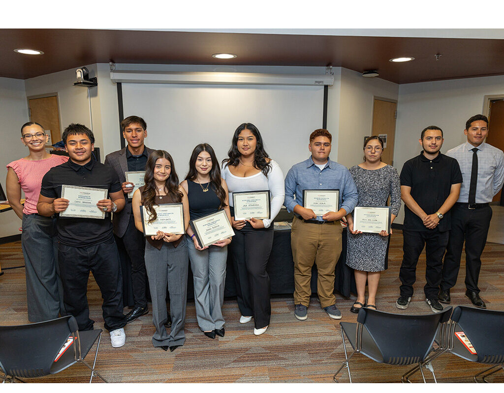 A group of high schoolers holding certificates and college staff stand for a group photo.