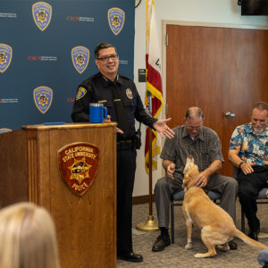 Department of Police Services Chief Alfredo B. Fernandez stands to the side of the podium, with Sergeants Abney and Messmore and K9 officer Daisy off to the right.