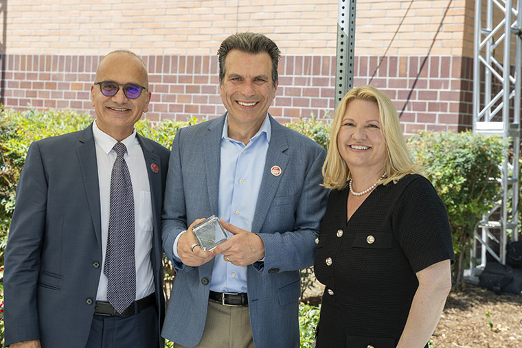 Andrew Anagnost holds a glass cube that commemorates the naming of the Andrew J. Anagnost College of Engineering and Computer Science. He is standing flanked by Houssam Toutanji and 鶹AV President Erika D. Beck.