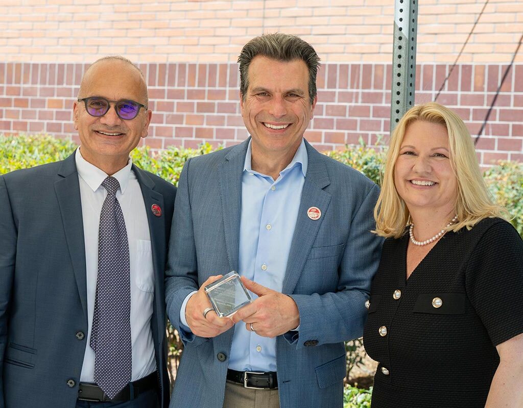 Andrew Anagnost holds a glass cube that commemorates the naming of the Andrew J. Anagnost College of Engineering and Computer Science. He is standing flanked by Houssam Toutanji and CSUN President Erika D. Beck.