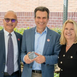 Andrew Anagnost holds a glass cube that commemorates the naming of the Andrew J. Anagnost College of Engineering and Computer Science. He is standing flanked by Houssam Toutanji and CSUN President Erika D. Beck.