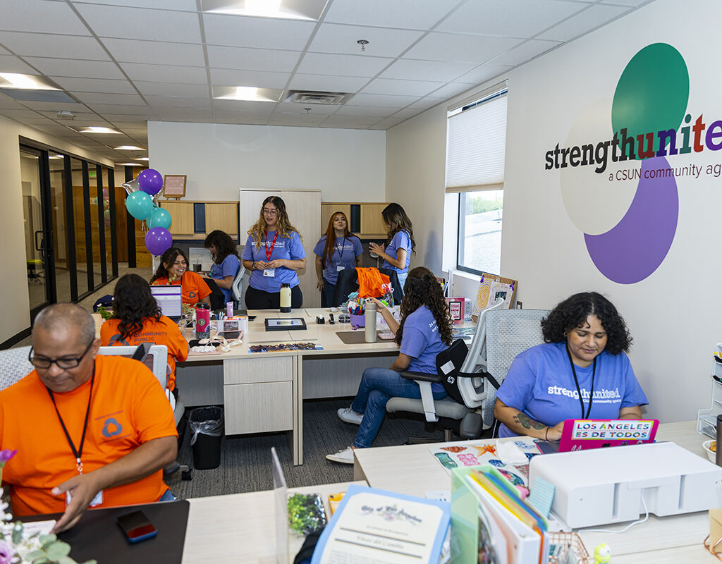 Students and staff sit and stand in the reception area of a new Strength United office.