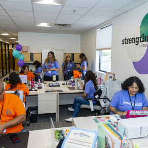 Students and staff sit and stand in the reception area of a new Strength United office.