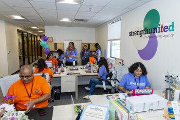 Students and staff sit and stand in the reception area of a new Strength United office.