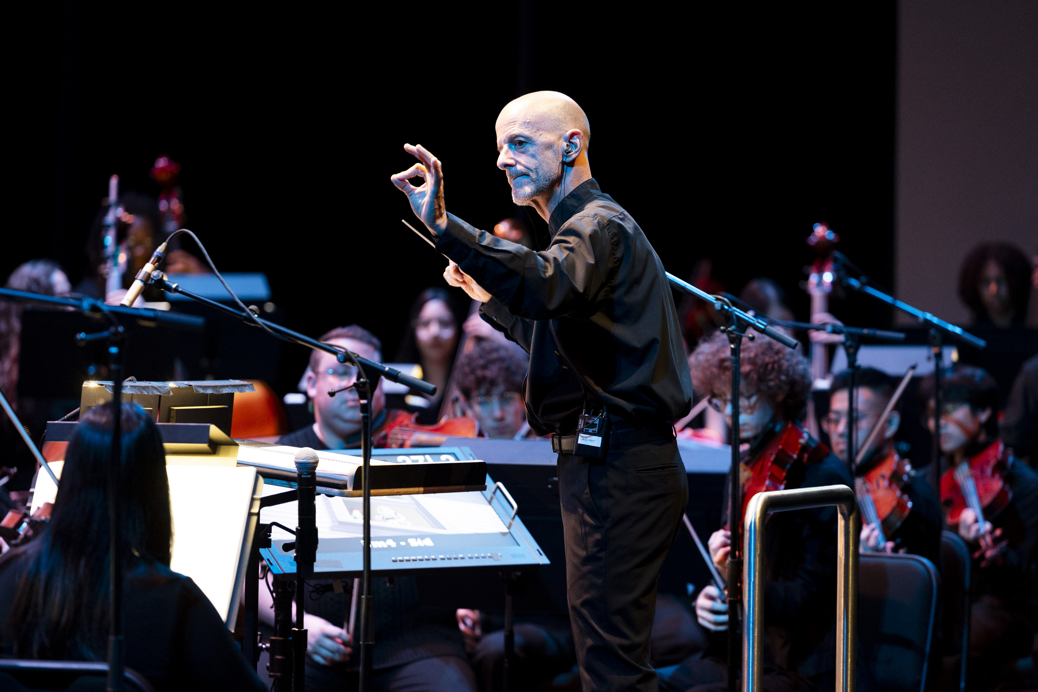 A man conducts a college orchestra during a concert at The Soraya. 