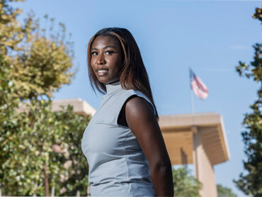 Kaitlyn Bryant in the foreground, the University Library with the American flag flying in the background.