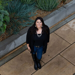 Jenee Ornelas looks up from the sidewalk in front of the University Library. The camera's perspective is looking down at her.