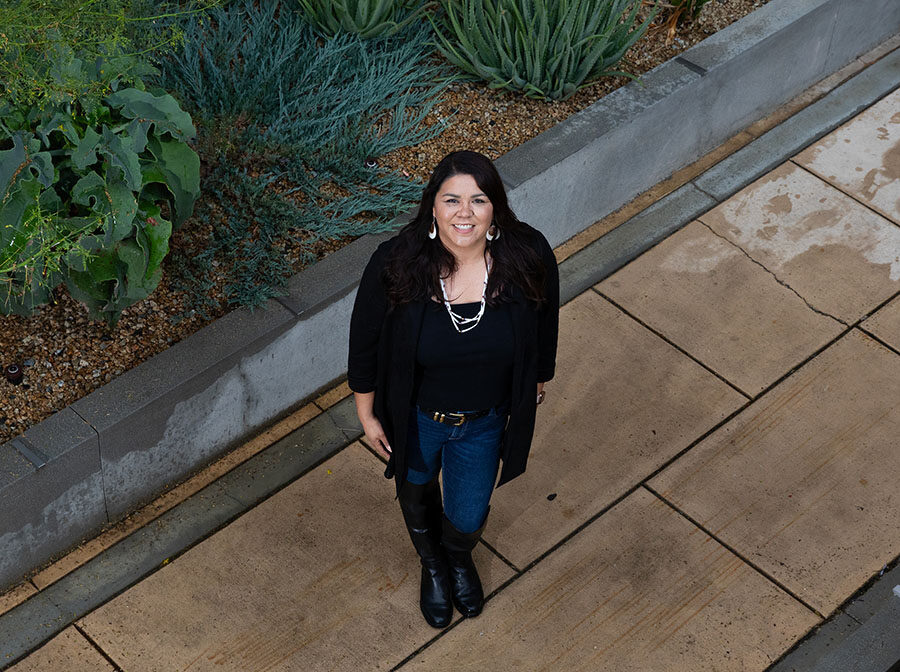 Jenee Ornelas looks up from the sidewalk in front of the University Library. The camera's perspective is looking down at her.