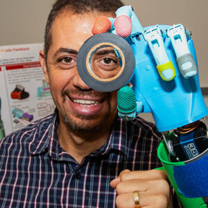 Peter Bishay holds up a reel of tape to his eye with a prosthetic hand.