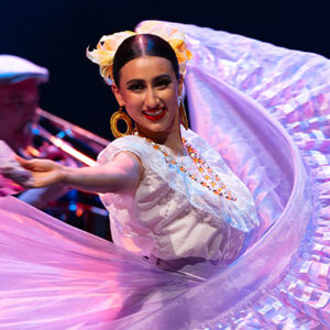 Dancer in flowing white dress reaches out to the audience.