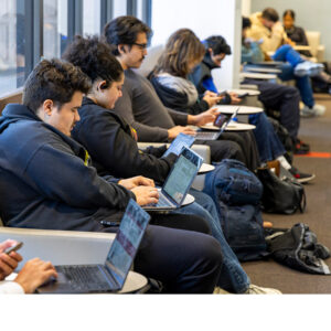Students sit in a classroom, using laptops.