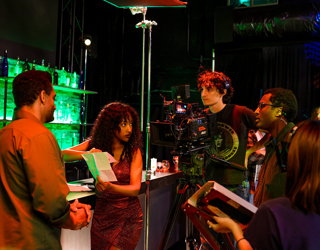 A director works with actors on a nightclub set