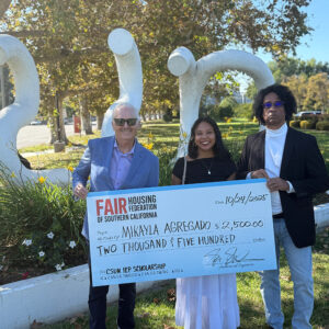 Three people stand in front of the CSUN sculpture holding a large, ceremonial check.