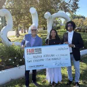 Three people stand in front of the CSUN sculpture holding a large, ceremonial check.