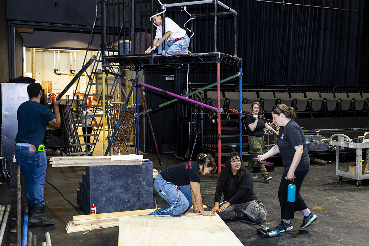 Students and staff build a theater set in a black box theater.