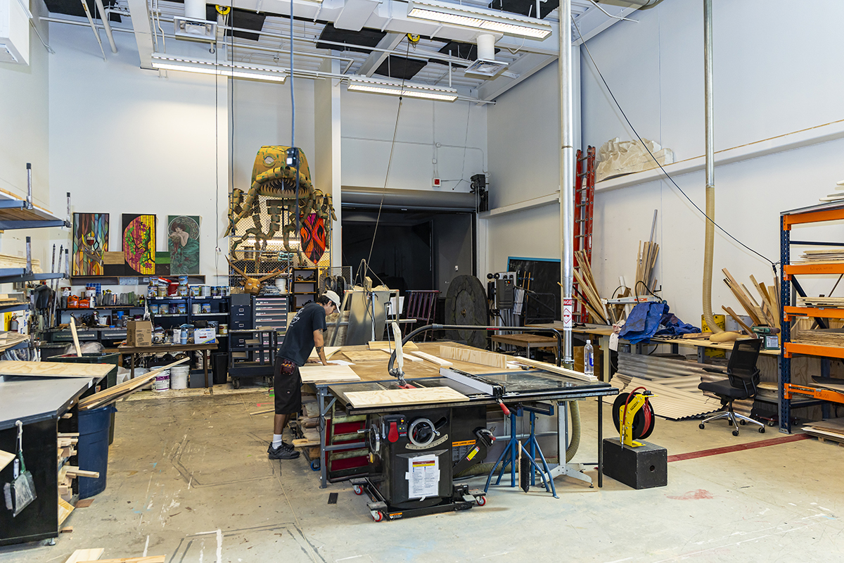 A wide shot of a student working in a workshop where theater backgrounds are built.
