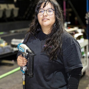Portrait of CSUN theatre major Arianna Alonso, holding a drill in a workshop
