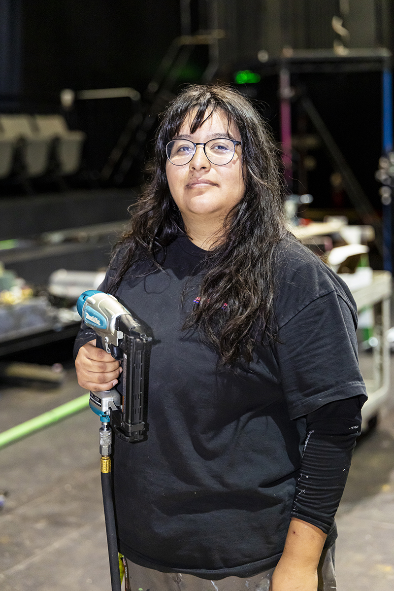 Portrait of CSUN theatre major Arianna Alonso, holding a drill in a workshop