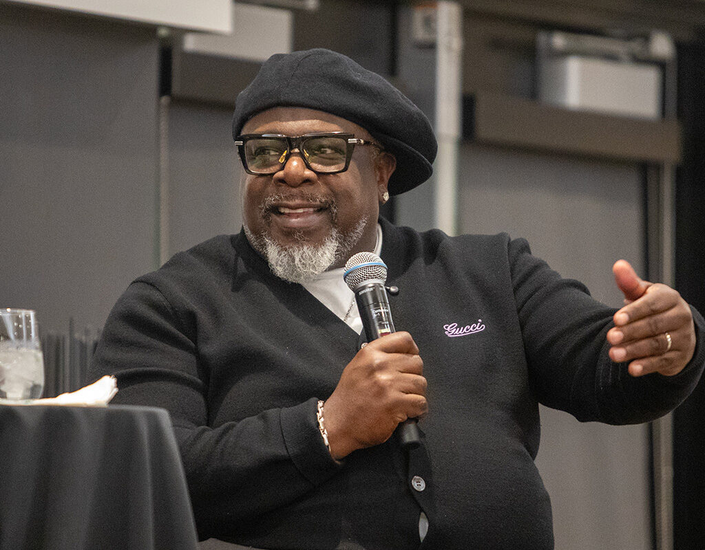 Cedric the Entertainer, seated, holds a microphone.