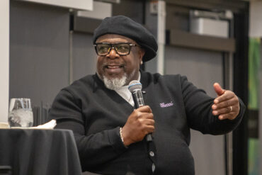 Cedric the Entertainer, seated, holds a microphone.