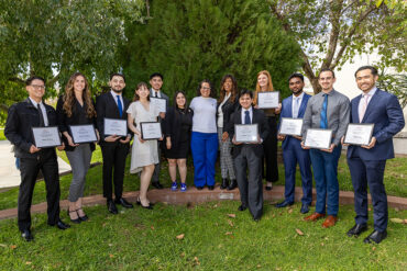 Students, holding certificates, pose for a group photo with scholarship benefactors.