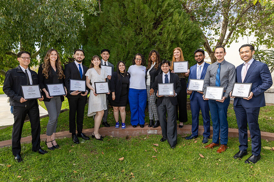 Students, holding certificates, pose for a group photo with scholarship benefactors.