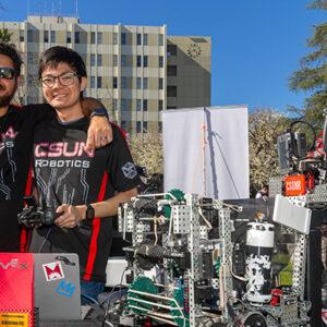 Two students wearing black shirts with CSUN Robotics pose for the camera.