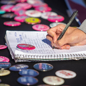 A notebook and buttons decorate a table.