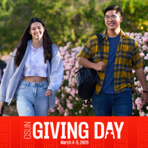 Two students walk together by rose bushes. Red banner across the bottom of the photo says CSUN Giving Day, March 4-5, 2026.