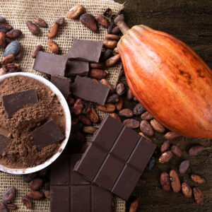 Detail of cocoa fruit with pieces of chocolate and cocoa powder on raw cocoa beans.