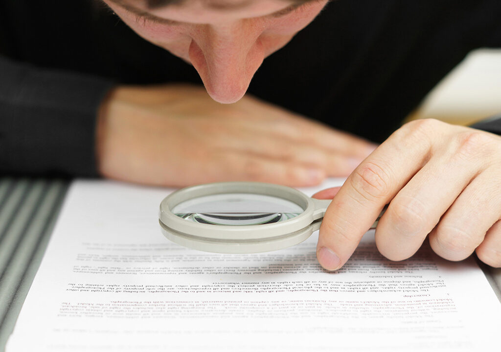 Man examining a document with a magnifying glass