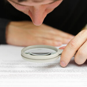 Man examining a document with a magnifying glass