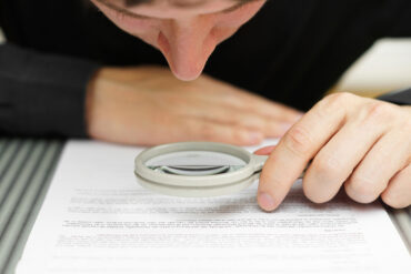 Man examining a document with a magnifying glass