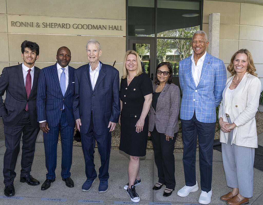 A group of well-dressed university officials in front of a building.