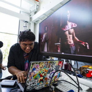 A student working on a colorful laptop reviews an image of an actor dressed as Flash Gordon.