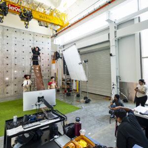 A wide shot of a photoshoot in an engineering lab of actors dressed as "Flash Gordon" characters
