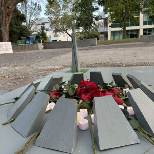A wooden replica of an Armenian Genocide memorial eternal flame is covered with red roses and battery-powered candles. It is sitting in the middle of Matador Square.