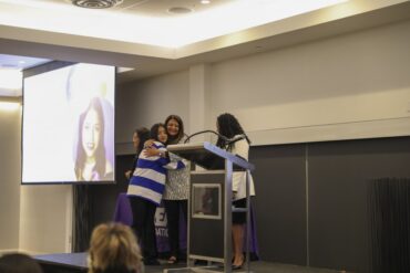 Student Karla Moreno hugs Senior Director of the Equal Opportunity Program Shiva Parsa as Moreno is recognized for receiving the scholarship. CREA Foundation Executive Director Arvetta Jideonwo stands along side the pair on the stage. Photos provided by Crystal Gomez.
